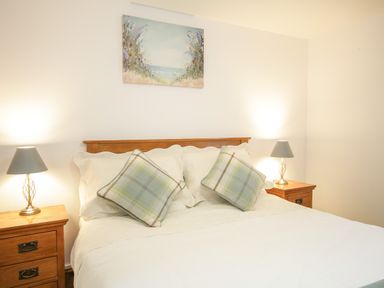 A bedroom with a bed with plaid pillows and two bedside tables with lamps at Pendre Uchaf in Melin-y-Wig near Ruthin