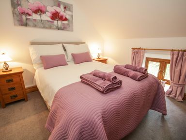 A bedroom with a double bed two bedside tables lamps and folded towels at Pendre Uchaf in Melin-y-Wig near Ruthin
