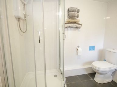 A bathroom with a shower enclosure and a toilet with towels on a rack at Pendre Uchaf in Melin-y-Wig near Ruthin