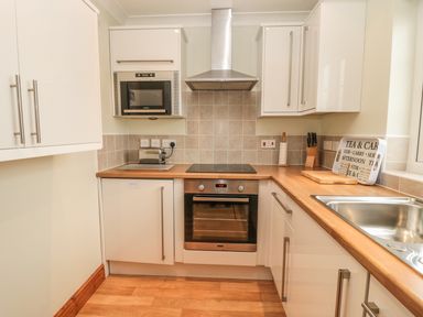 A kitchen with wooden countertops stainless steel sink oven microwave toaster and cabinets at White Rock Cottage in Beadnell
