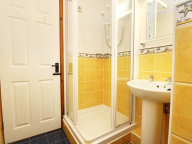 A bathroom with a shower enclosure sink and a door at The Shippon Near Launceston