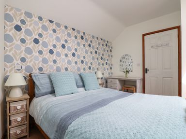 A bedroom with a bed table lamps wallpaper and a dressing table at The Wagon House in Polyphant near Launceston
