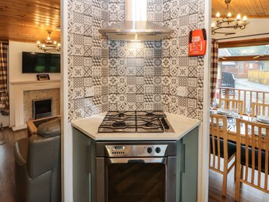A kitchen with a gas stove and oven next to a living room and dining area at Langdale Lodge 15 White Cross Bay near Troutbeck Bridge