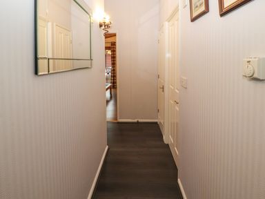 A narrow hallway with dark flooring white walls a wall-mounted mirror light switch and thermostat at Langdale Lodge 15 White Cross Bay near Troutbeck Bridge