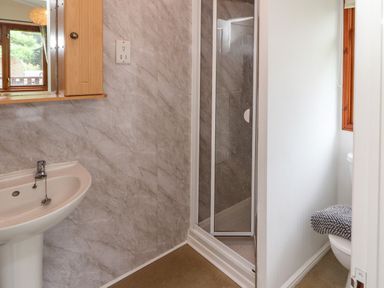 A bathroom with a sink a shower cubicle and a toilet with a towel on the lid at Langdale Lodge 15 White Cross Bay near Troutbeck Bridge