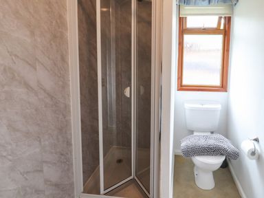 A bathroom with a shower enclosure and a toilet under a window at Langdale Lodge 15 White Cross Bay near Troutbeck Bridge
