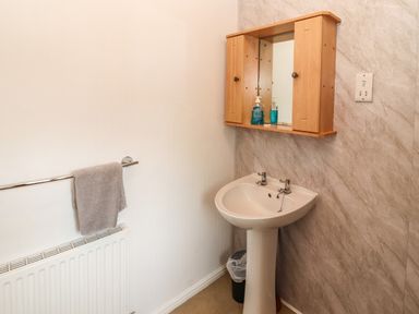 A bathroom with a pedestal sink and a wooden mirrored cabinet above at Langdale Lodge 15 White Cross Bay near Troutbeck Bridge