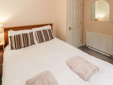 A bedroom with a double bed striped pillows folded towels bedside table lamp door mirror and radiator at Langdale Lodge 15 White Cross Bay near Troutbeck Bridge