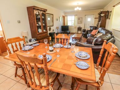 A dining area with a wooden table set for six and a living room with leather sofas at Drovers Rest in Otterburn