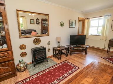 A living room with a wood stove a television and wooden furniture at Drovers Rest in Otterburn