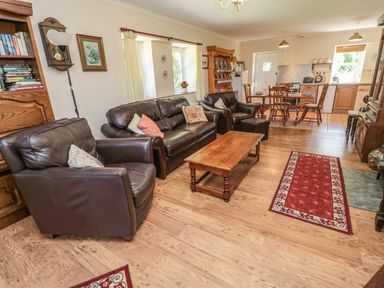 A living room with leather sofas a coffee table a dining table with chairs and a kitchen area at Drovers Rest in Otterburn