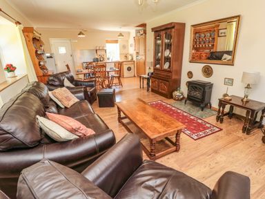 A living room with leather sofas wooden coffee table and a dining area with chairs at Drovers Rest in Otterburn