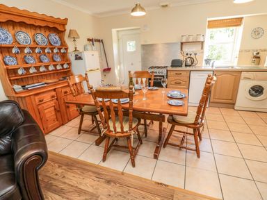 A kitchen and dining area with wooden table and chairs blue and white dishes on a hutch and kitchen appliances at Drovers Rest in Otterburn