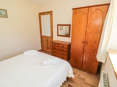 A bedroom with a wooden wardrobe chest of drawers and a bed with white bedding at Drovers Rest in Otterburn