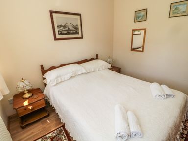 A bedroom with a double bed side tables framed pictures and rolled towels at Drovers Rest in Otterburn