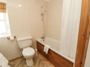 A bathroom with a toilet bathtub shower and a white shower curtain at Drovers Rest in Otterburn