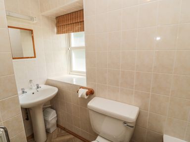 A bathroom with a toilet sink mirror window and a small trash bin at Drovers Rest in Otterburn