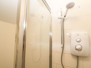 A shower area with a handheld showerhead and an electric shower control at Stables Cottage in Bowerhill near Melksham