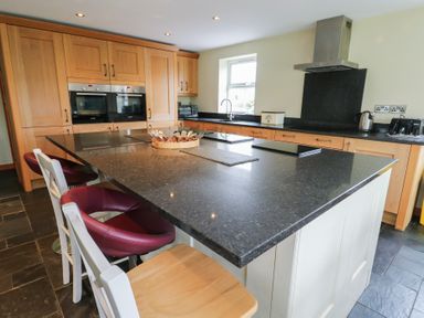 A kitchen with wooden cabinetry and a central island at Chapel House Elim near Llanddeusant