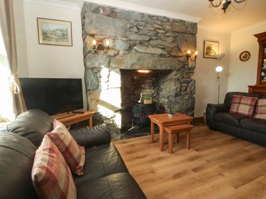 A living room with a sofa, television, and fireplace at Tyddyn in Dyffryn Ardudwy
