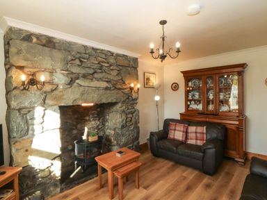 A living room with a stone fireplace and wooden furniture at Tyddyn in Dyffryn Ardudwy