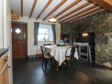 A kitchen with a dining table and stove at Tyddyn in Dyffryn Ardudwy
