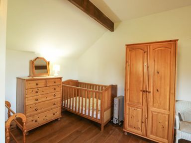 A bedroom with a crib and a dresser at Tyddyn in Dyffryn Ardudwy