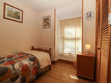 A bedroom with a bed, lamp, and artwork at Tyddyn in Dyffryn Ardudwy
