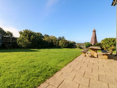 A garden with a table and parasol at Tyddyn in Dyffryn Ardudwy