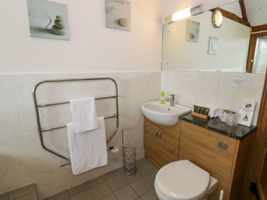 A bathroom with a toilet sink and towel rack with two towels at Beesoni Lodge Castlemorton near Malvern