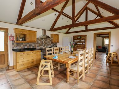 A kitchen with wooden dining table and chairs under exposed wooden beams at Beesoni Lodge Castlemorton near Malvern
