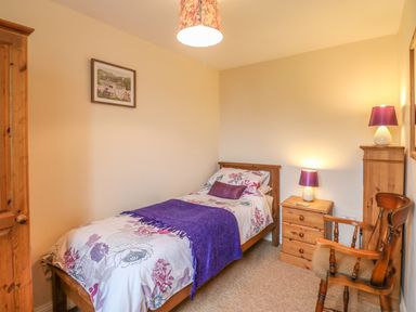 A small bedroom with a single bed a wooden wardrobe two bedside lamps and a wooden chair at 1 Cowdea Farm Bettiscombe near Beaminster and Bridport