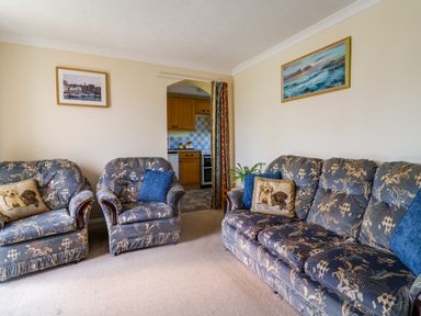 A living room with patterned sofas and pillows and a kitchen visible through an archway at 1 Cowdea Farm in Bettiscombe near Beaminster and Bridport