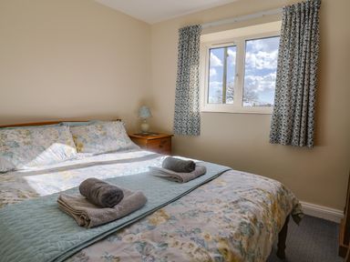 A bedroom with a bed covered with floral bedding two bedside tables with a lamp and towels on the bed at 1 Cowdea Farm Bettiscombe near Beaminster and Bridport