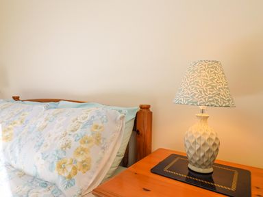 A bed with floral pillows and a wooden bedside table with a lamp at 1 Cowdea Farm Bettiscombe near Beaminster and Bridport