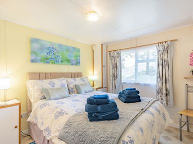 A bedroom with a bed covered in floral bedding and blue towels on top at Bluebell Cottage in Maenan near Llanrwst