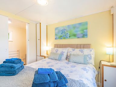 A bedroom with a bed covered in floral bedding and blue towels at the foot of the bed at Bluebell Cottage in Maenan near Llanrwst