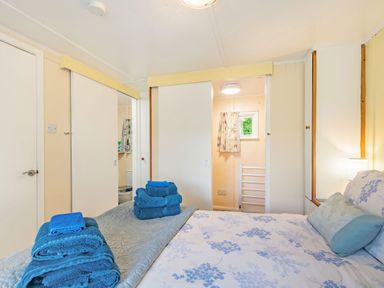 A bedroom with a bed with blue and white floral bedding and folded blue towels on the bed at Bluebell Cottage in Maenan near Llanrwst