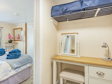 A bedroom with a bed and blue towels and a desk with a mirror and lamp at Bluebell Cottage in Maenan near Llanrwst