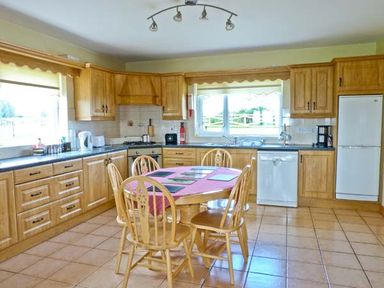 A kitchen with wooden cabinets a table with chairs and appliances at Sallywood House in Carn near Ballybofey County Donegal