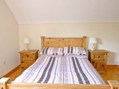 A bedroom with a wooden bed and two bedside tables with lamps at Sallywood House in Carn near Ballybofey County Donegal