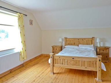 A bedroom with a wooden bed and two bedside tables with lamps at Sallywood House in Carn near Ballybofey County Donegal