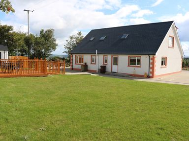 A white house with black roof windows and a wooden deck on a grassy lawn at Sallywood House in Carn near Ballybofey County Donegal