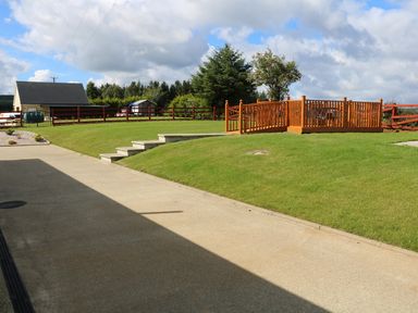 An outdoor area with grass lawn steps a wooden deck and a small building in the background at Sallywood House in Carn near Ballybofey County Donegal