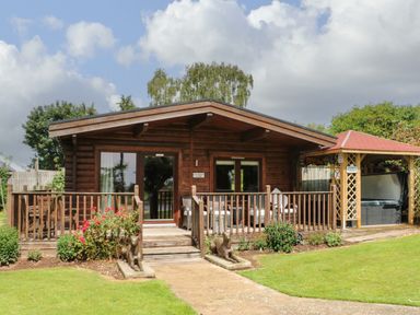 A wooden lodge with a porch and garden statues in front at Cornfield in Northallerton