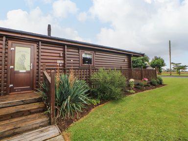 A wooden cabin with stairs and a garden in front at Cornfield in Northallerton