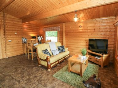 A living room with a yellow sofa and wooden coffee table facing a television at Cornfield in Northallerton