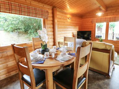 A wooden dining table set for four with dishes and cups in a log cabin dining area at Cornfield in Northallerton