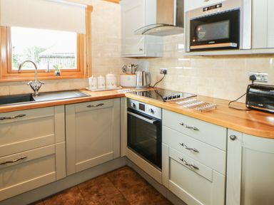 A kitchen with a wooden countertop a microwave an oven a kettle a toaster and a window at Cornfield in Northallerton