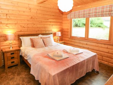 A bedroom with a double bed two bedside tables with lamps and a window with a plaid curtain at Cornfield in Northallerton